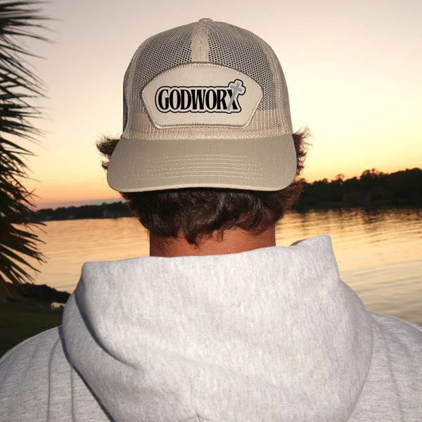 a person wearing a christian godworx logo mesh hat looking at a sunset