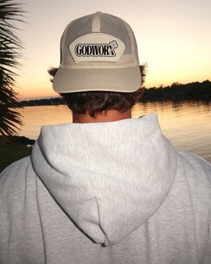 Person wearing a cap with a godworx logo by a lake at sunset